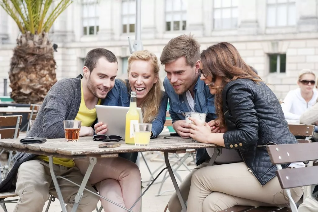 Group with tablet in hostel cafe Group with tablet in hostel cafe
