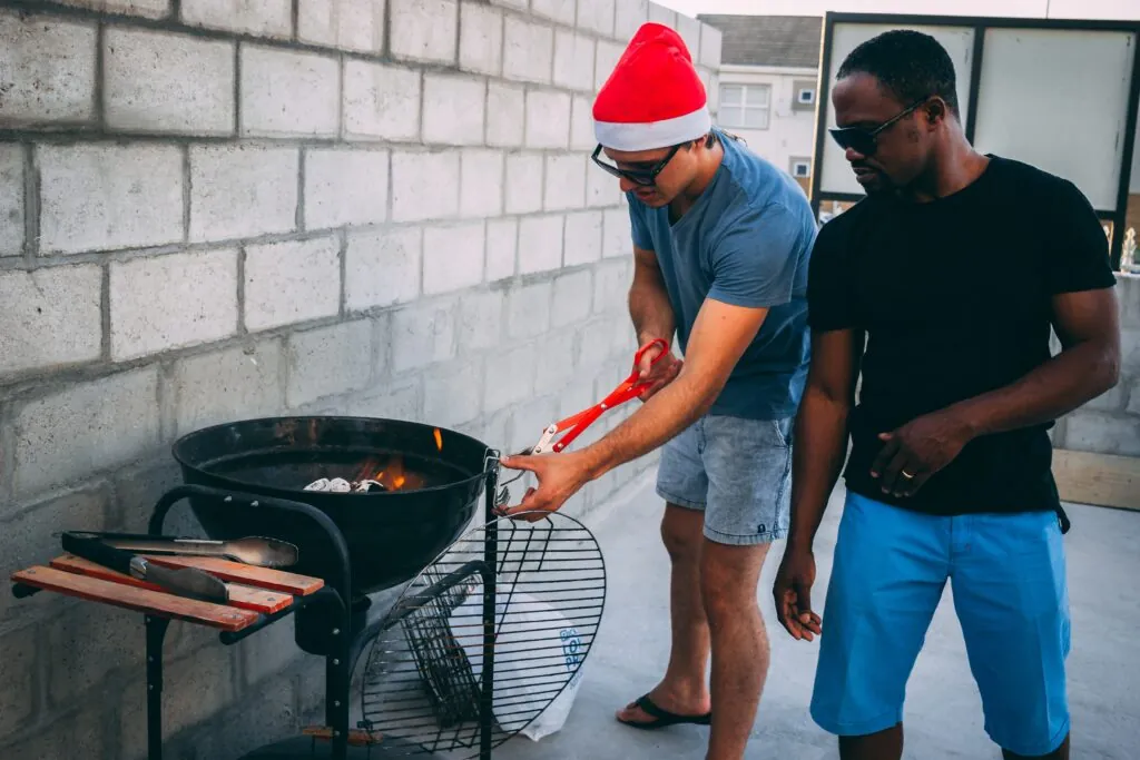 man wearing a santa hat lighting a bbq