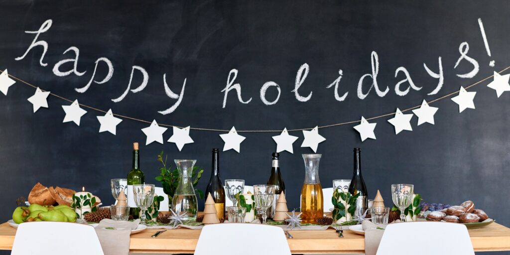 'happy holidays' written on a chalk board behind a decorated dinner table